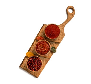 There are three bowls and spoons on the kitchen board with spicy oriental spices