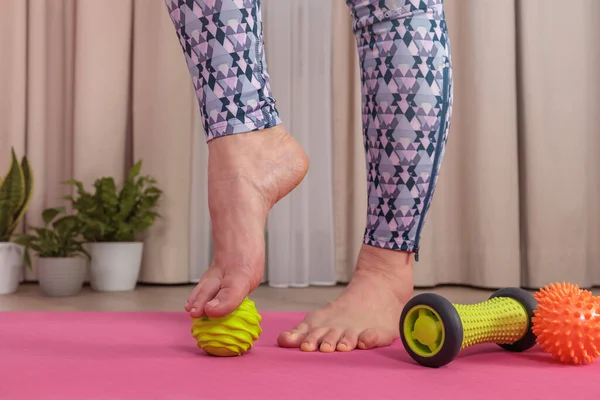 Yeşil bir topla kendine ayak masajı yapan bir kızın ayaklarına yakın çekim.