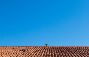 Açık mavi gökyüzünün arkaplanına karşı, eski fayanslardan yapılmış karşıt turuncu bir çatı