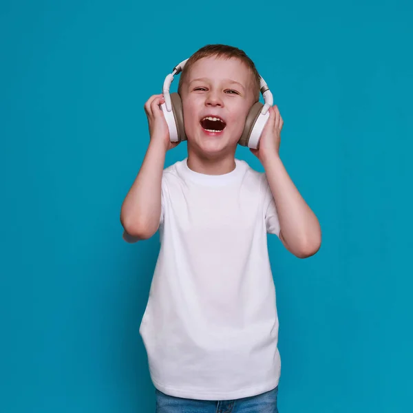 Mocap, mały Europejczyk w białej koszulce i słuchawkach na niebieskim tle — Zdjęcie stockowe