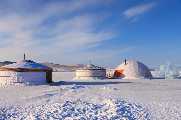 Mongolian traditional yurt in a snowy desert with mountains in the background