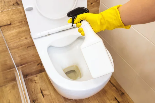Nahaufnahme der Hände in Handschuhen mit Reinigungslösung zur Desinfektion der Toilette, Flaschenattrappe — Stockfoto