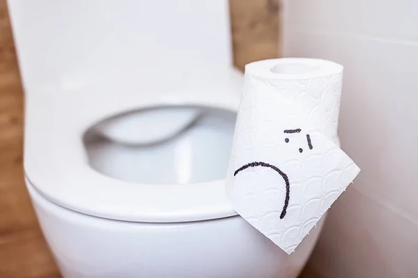 Gulungan tisu toilet dengan wajah sedih hang berdiri di toilet dengan tutup terbuka — Stok Foto