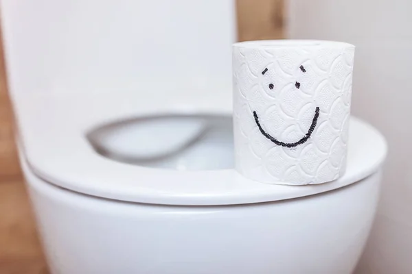 Close-up of toilet paper with a painted happy face, on a toilet with an open lid — Stock Photo, Image