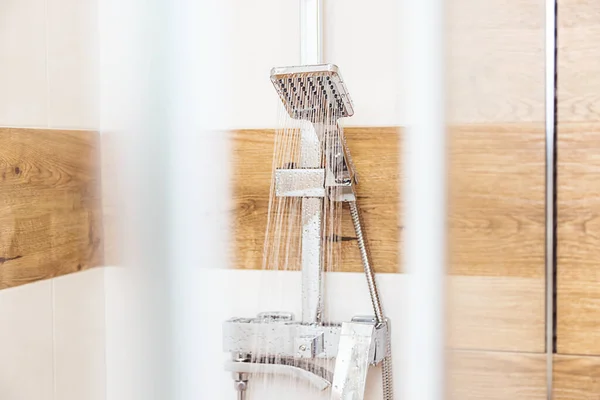 Primer plano de un grifo desde el que fluye agua limpia en una cabina de ducha de vidrio — Foto de Stock