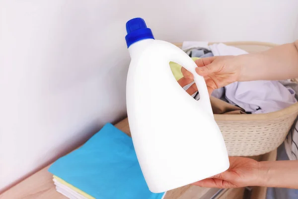 Close-up, in the hands of a woman is a large white bottle, a template for a label, logo. Liquid detergent, fabric softener, bleach, laundry detergent. copy paste white background