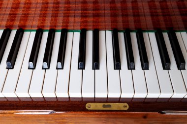 Yakın plan, kahverengi piyano. Piyano tuşları siyah ve beyaz, üst görünüm, düz güneş. Müzik eğitimi konsepti. Arkaplan, afiş veya afiş için kapak