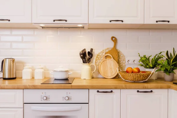 Yeni, beyaz mutfak, eski tarz bir dairede detaylar, yakın çekim, dik açı, arka ışıklandırma. Ahşap masa ve zemin. Eski usul ahşap çanak çömlek masada. Metnin için arkaplan