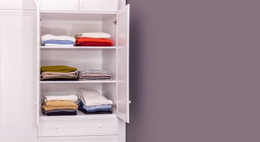 Yakın plan, eşyaların düzgünce istiflendiği büyük beyaz bir dolap. Tasarım için yapıştır alanı kopyala. Düzen konsepti, mekan düzeni, akıl sağlığı. Hepsi raflarda.