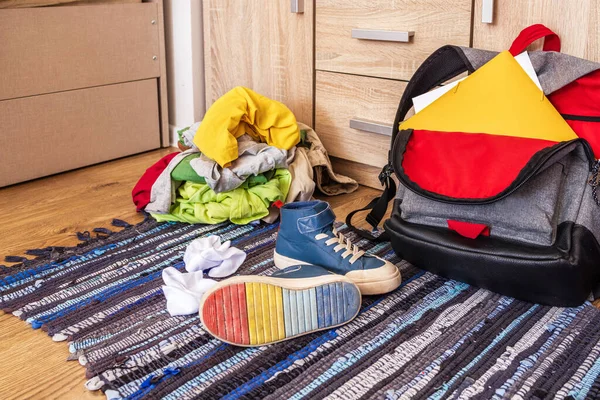 Yakın plan, ergen eşyaları, okul çantası, spor ayakkabıları, renkli giysiler yere saçılmış. Yakın plan, yan görüş. Düzensizlik kavramı, çocuğun zor, geçiş yaşı