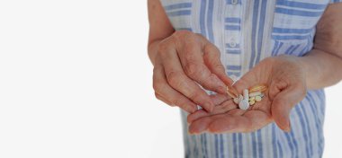 Yakın plan, beyaz arka planda yaşlı bir kadın. Yaşlı bir kadının elinde hastalıklar için birçok farklı ilaç ve vitamin vardır. Yaşlılarda hastalık önleme kavramı