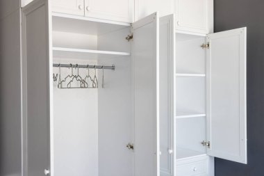 Yakın plan, beyaz gardırop, raflar ve iş kıyafetleri için askılar, koyu gri arka plan. Modern bir oda, minimalist tarzda bir daire. Alan düzenleme kavramı