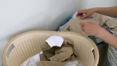 Kirli çamaşırları toplayan ve onları leğene koyan bir kadının elleri. Kadınların ev işleri, çamaşır yıkama tozu, çamaşır yıkama, çamaşır yıkama. Ev işleri, günlük kadın işleri.