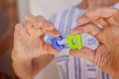 Yakın plan, kadın ellerinde C-A harfleri, kalsiyum, eklem, kemik, eklem iltihabı, artrit, yaşlılarda önleme ve tedavi kavramı tutuyor. Biyohowerlar, haplar, vücut desteği