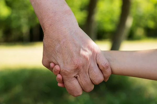 Close-up. Old wrinkled hands and young beautiful hands of a child. Care concept, different generations. Joint diseases in the elderly, diabetes mellitus, padagra, arthritis