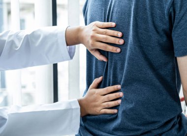 Kadın fizyoterapist, hastanın omuriliğini, masaj ve sağlık kliniğinde fiziksel egzersiz yaparken tedavi ve iyileşme için kontrol ediyor.