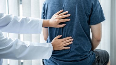 Kadın fizyoterapist, hastanın omuriliğini, masaj ve sağlık kliniğinde fiziksel egzersiz yaparken tedavi ve iyileşme için kontrol ediyor.