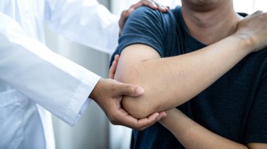 Kadın fizyoterapist, sağlık kliniğinde esneyerek ve fiziksel egzersiz yaparak hastanın omuz yaralanmasından sonra tedavi ve rehabilitasyon yapıyor.