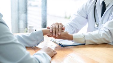 Erkek doktor, panoya reçete yazdıktan sonra tedaviyi teşvik etmek ve açıklamak için el ele tutuşup, hastalığın klinikteki hastaya incelenmesinin sonucunu tartışır.