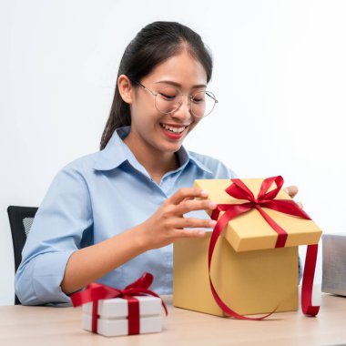 Mutlu kadın gülümsüyor ve hediye kutusuna bakarken kırmızı kurdeleyle hediye kutusunu açıyor. Çok heyecanlı ve mutlu bir şekilde Noel ve yeni yılı kutluyor.