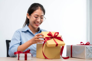 Mutlu kadın gülümsüyor ve hediye kutusuna bakarken kırmızı kurdeleyle hediye kutusunu açıyor. Çok heyecanlı ve mutlu bir şekilde Noel ve yeni yılı kutluyor.