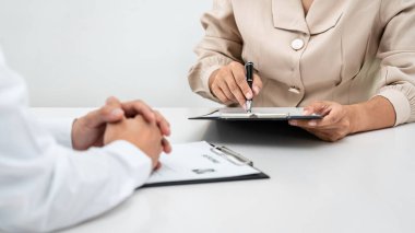 Kadın işveren, adaylara soru sorarak ve iş tanımı hakkında iş görüşmesine başvururken başvuranlara açıklama yaparak özgeçmişlerine işaret ediyor.