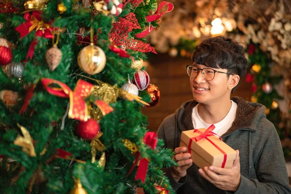 Ázsiai Férfi Pulóverben Mosolyog Kezében Ajándék Míg Díszített Karácsonyfa Csillogó — Stock Fotó