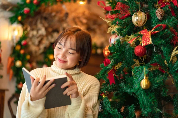 Женщина Свитере Читает Книгу Сидя Перед Рождественской Елкой Украшая Празднику — стоковое фото