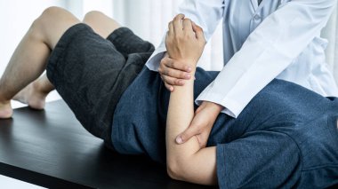 Tedavi ve rehabilitasyon yapan kadın fizyoterapist, sağlık kliniğinde esneyerek ve fiziksel egzersiz yaparak hastanın kolları ve bilekleri yaralı.