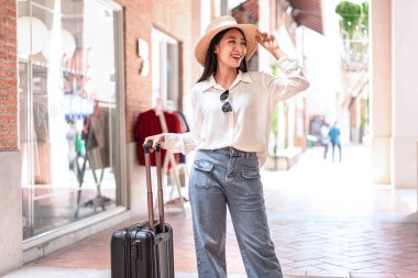 Gülümseyen kadın yolcu siyah bavul taşıyordu. Havaalanında yolcu almaya gidiyordu. Seyahat konsepti..