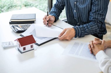 Emlak komisyoncusu analizi ve emlak alım sözleşmesi imzalamak için müşteriye emlak kredisi verme kararı veren banka çalışanları, mortgage kredi onayı öneriyorlar..