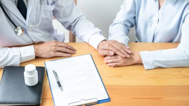 Erkek doktor, panoya reçete yazdıktan sonra tedaviyi teşvik etmek ve açıklamak için el ele tutuşup, hastalığın klinikteki hastaya incelenmesinin sonucunu tartışır.