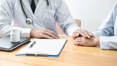 Erkek doktor, panoya reçete yazdıktan sonra tedaviyi teşvik etmek ve açıklamak için el ele tutuşup, hastalığın klinikteki hastaya incelenmesinin sonucunu tartışır.