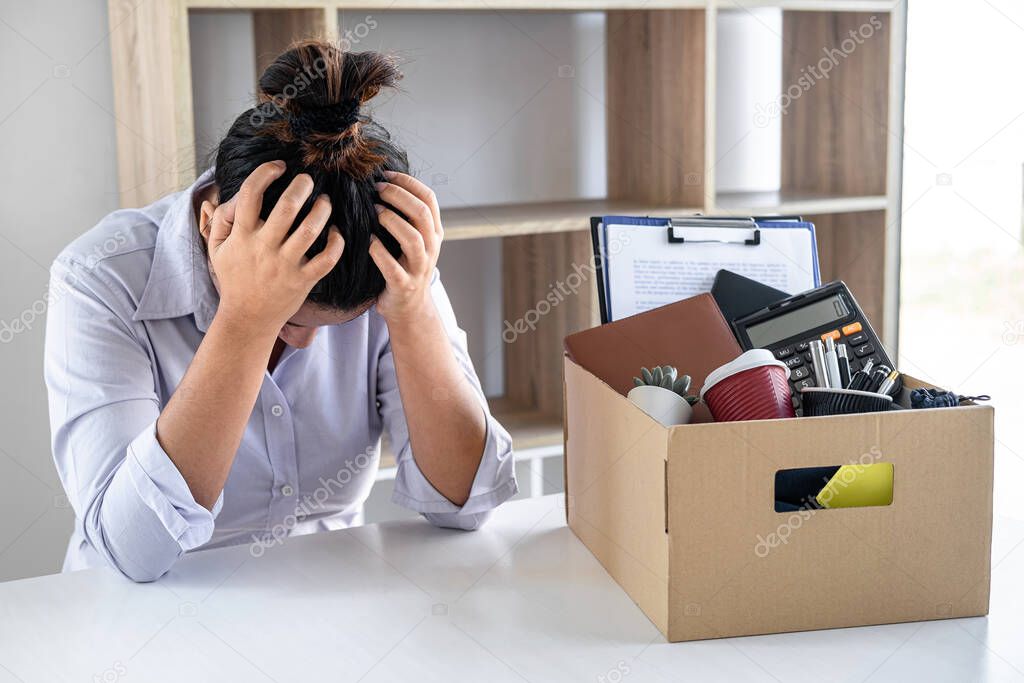 Images of business woman carrying packing up all his personal belongings and files into a brown cardboard box has frustrated and stressed to resignation and signing cancellation contract letter.