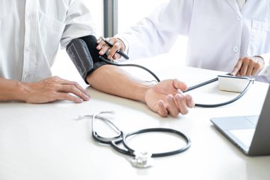 Doktor muayene hastasını ölçüyor ve hastanedeki semptom hastalığının tansiyonunu ölçüyor..
