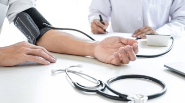 Doktor muayene hastasını ölçüyor ve hastanedeki semptom hastalığının tansiyonunu ölçüyor..