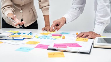 İki iş adamı, yeni iş projesiyle ilgili beyin fırtınası sırasında ofiste buluşurken masaya notlar koyuyor.