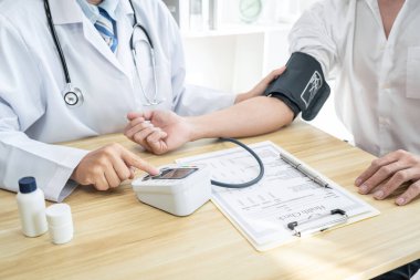 Doktor muayene hastasını ölçüyor ve hastane kliniğindeki semptom hastalığına kan basıncını ölçüyor..
