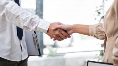 Kadın işveren yeni çalışanı tebrik etmek için el sıkışıyor. İş görüşmesinde başarılı olduktan sonra iş yerindeki toplantı odasında sözleşme imzaladı.