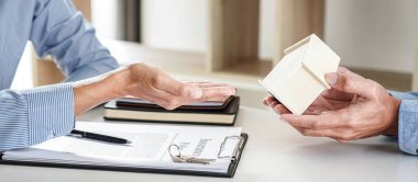 Emlak Satış Müdürü, kira kontratı ve konut sigortası için ipotek kredisi teklifiyle ilgili satış sözleşmesini imzaladıktan sonra müşteriye ev modelini ve anahtarları veriyor..