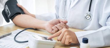 Doktor muayene hastasını ölçüyor ve hastane kliniğindeki semptom hastalığına kan basıncını ölçüyor..