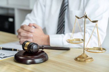 Mülk davasının evrakları, hukuk kitapları ve masa başında ahşap tokmakla çalışan erkek avukat..