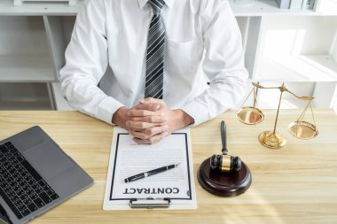 Erkek avukat ya da hukukçu, emlak davasının evrakları, hukuk kitapları ve ofisteki ahşap tokmak üzerinde çalışıyor..