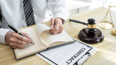 Mülk davasının evrakları, hukuk kitapları ve masa başında ahşap tokmakla çalışan erkek avukat..