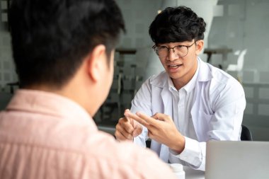 Teşhis konulduktan sonra hastalığın belirtilerini açıklayan erkek doktor, hastalara tıbbi özellikler ve uyuşturucu kullanımını klinikte yeni tedavi ve tavsiye tedavileri hakkında konuşmaya tavsiye ederken,