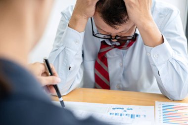 Erkek çalışan, yöneticinin iş belgesini kontrol etmesi ve ofis toplantısı sırasında yapılan işten şikayet etmesi üzerine başarısız proje yüzünden stres altında.