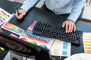 İş yerindeki grafik tabletinde renk seçimi ve çizim üzerine çalışan genç yaratıcı grafik tasarımcısı, seçim renklendirme için renk örneği grafikleri çizimi.