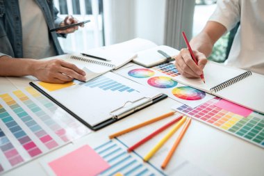 İş yerindeki grafik tabletinde renk seçimi ve çizim üzerine çalışan iki yaratıcı grafik tasarımcısı, renk örnekleri şeması.