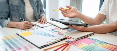 İş yerindeki grafik tabletinde renk seçimi ve çizim üzerine çalışan iki yaratıcı grafik tasarımcısı, renk örnekleri şeması.