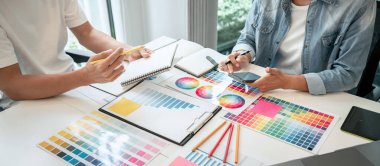 İş yerindeki grafik tabletinde renk seçimi ve çizim üzerine çalışan iki yaratıcı grafik tasarımcısı, renk örnekleri şeması.